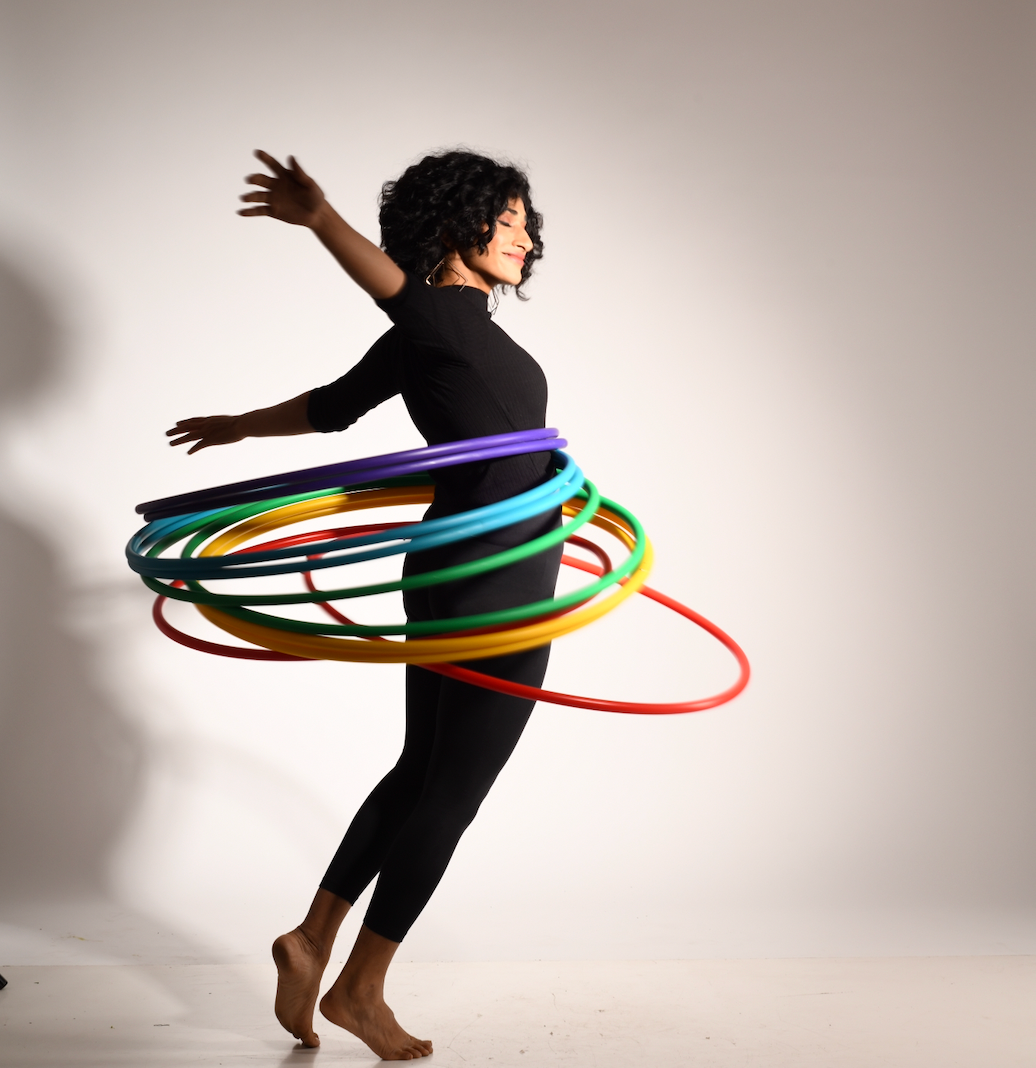 Eshna spinning colorful hula hoops on a plain background